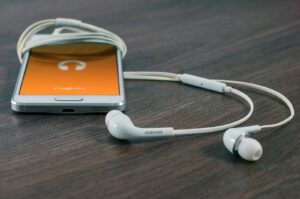 phone with earbuds being used to listen to best digital marketing podcasts